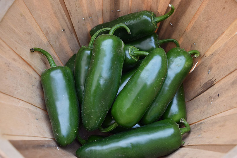 zelené jalapeños v dřevěném košíku